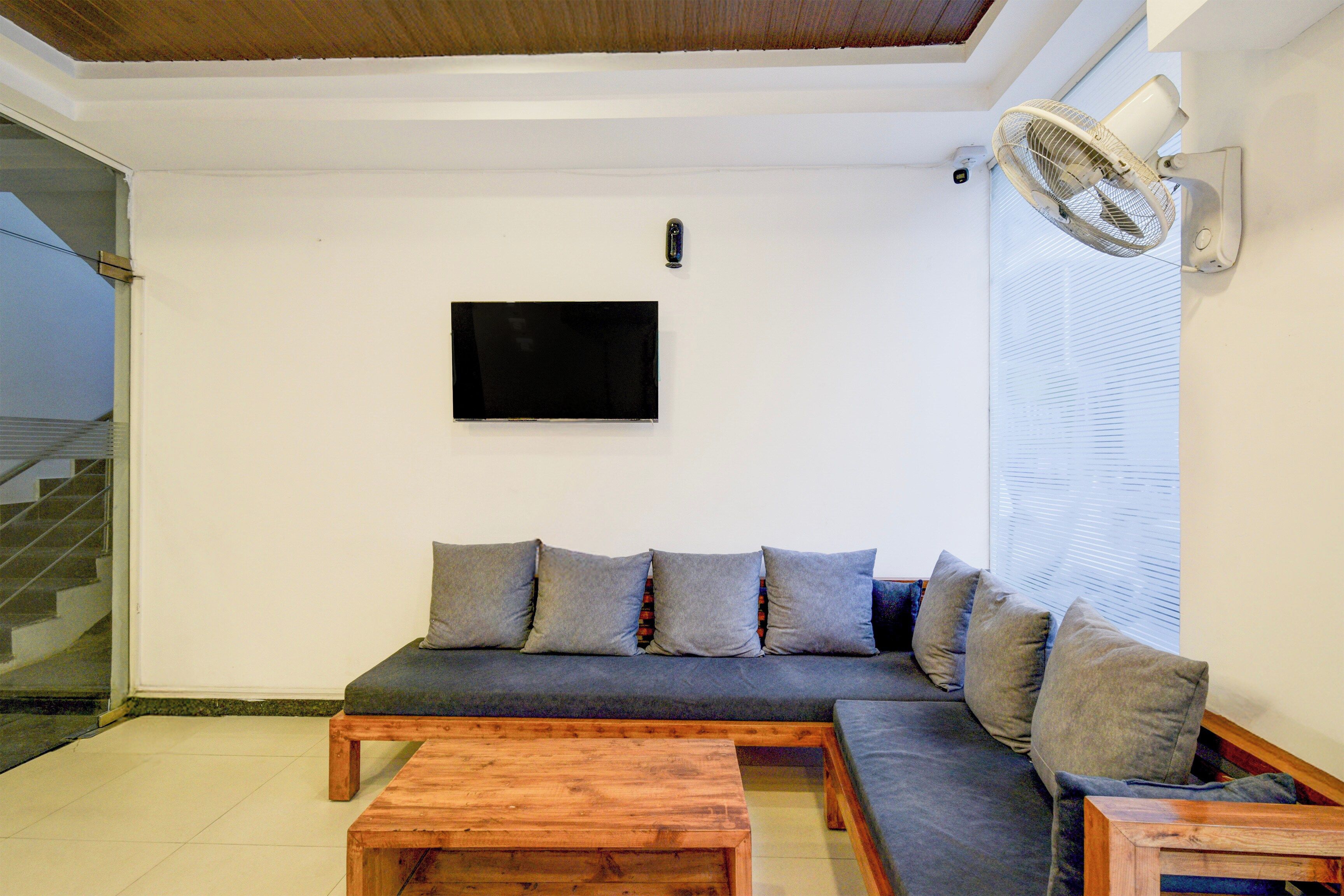 Una sala de estar con un sofá, una mesa de centro, un televisor y un ventilador de pie.