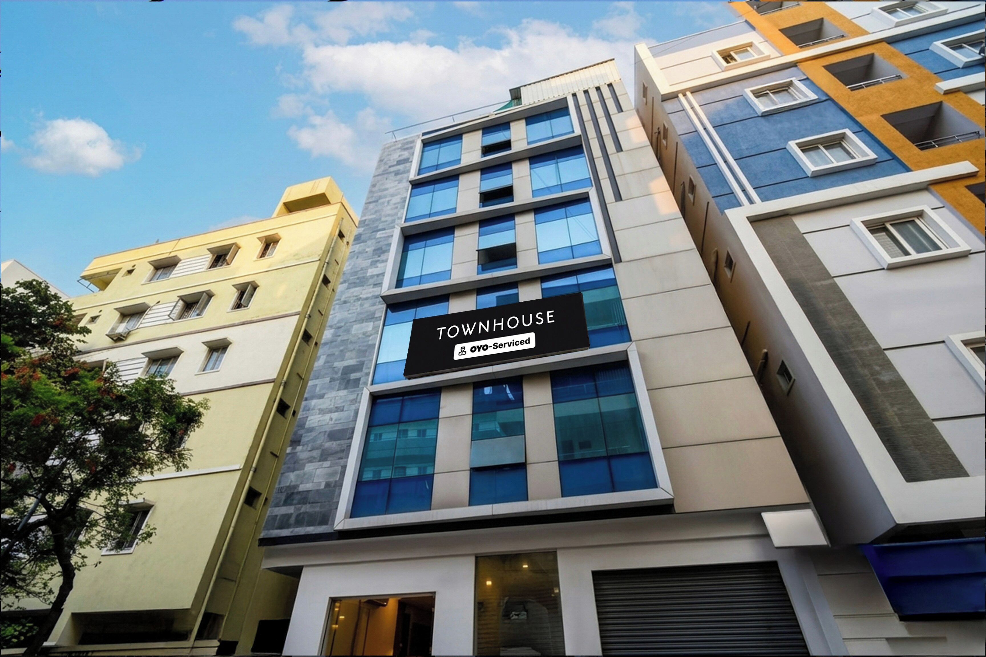 Un edificio de varios pisos con un cartel que dice 'TOWNHOUSE OYO-Serviced'.