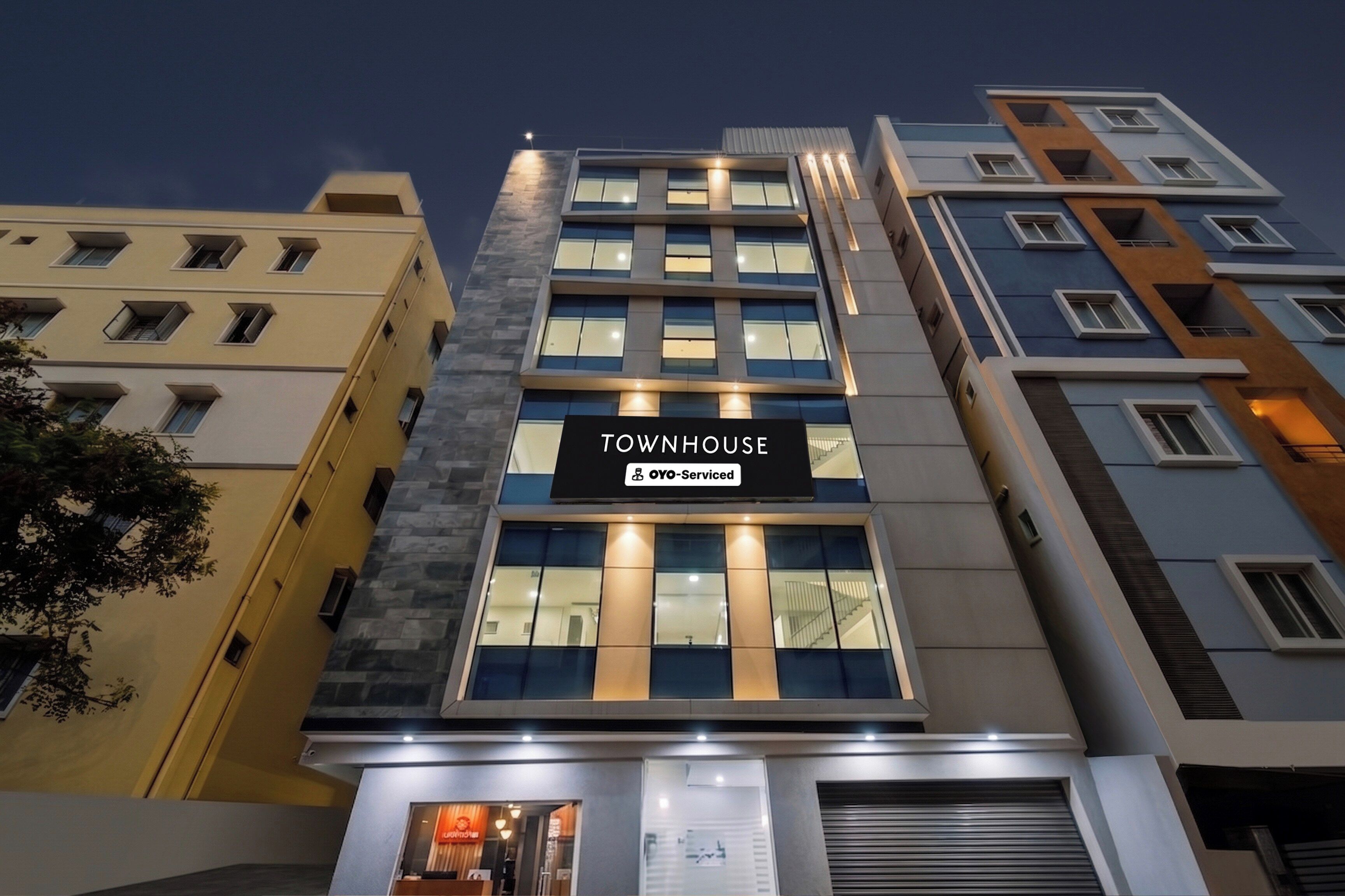 Un edificio de varios pisos con un letrero que dice 'TOWNHOUSE' y 'YOYO-SERVICED', indicando apartamentos con servicios.