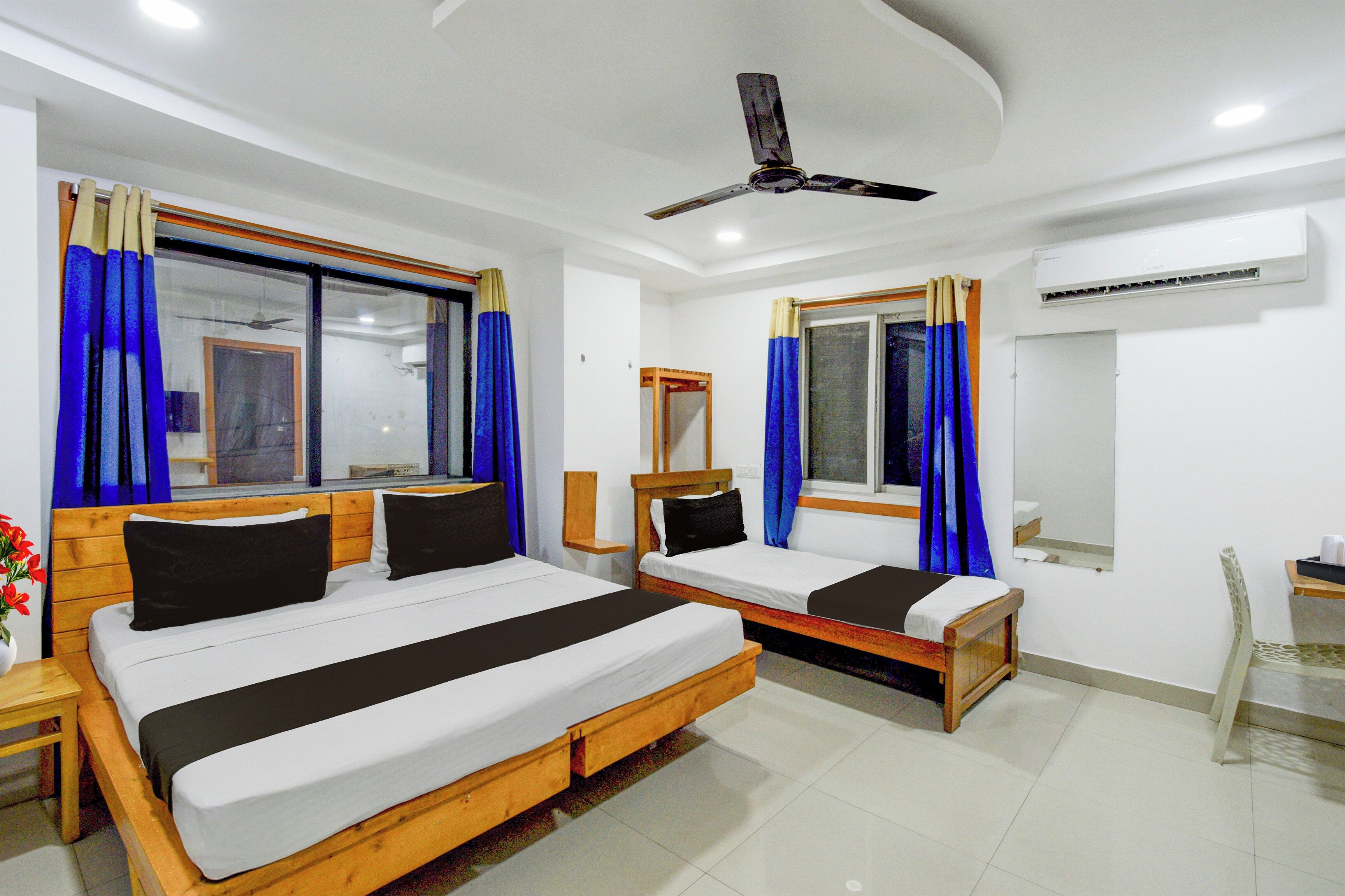 Habitación de hotel con dos camas, ventilador de techo y aire acondicionado.