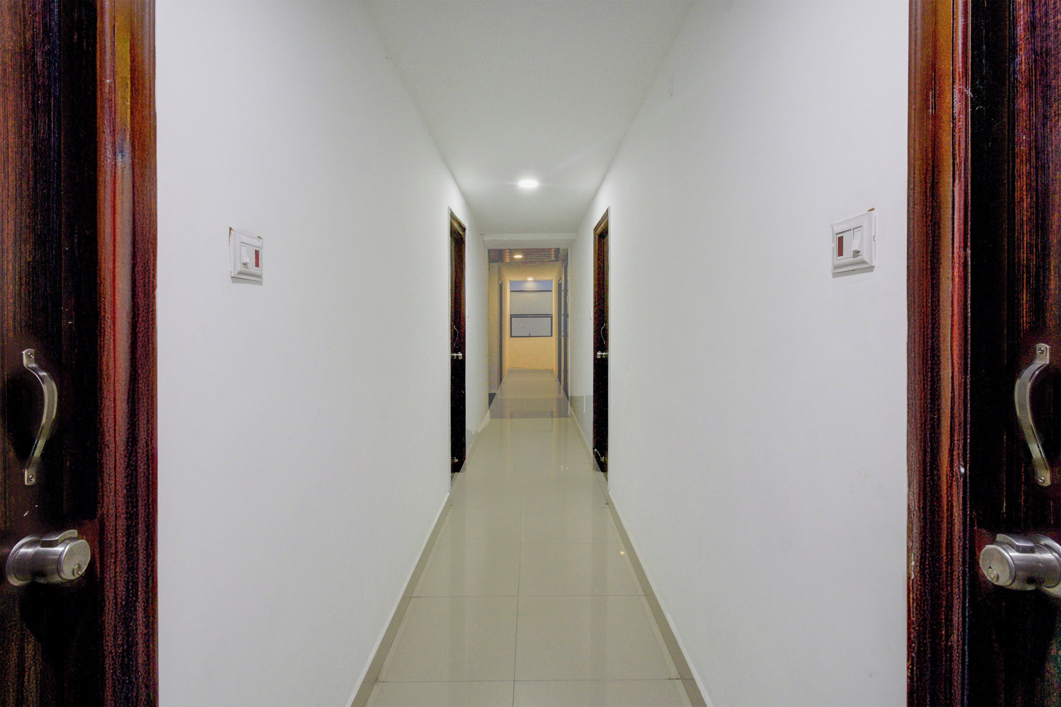 A corridor with doors on both sides, leading to a room with a window and a door at the end.