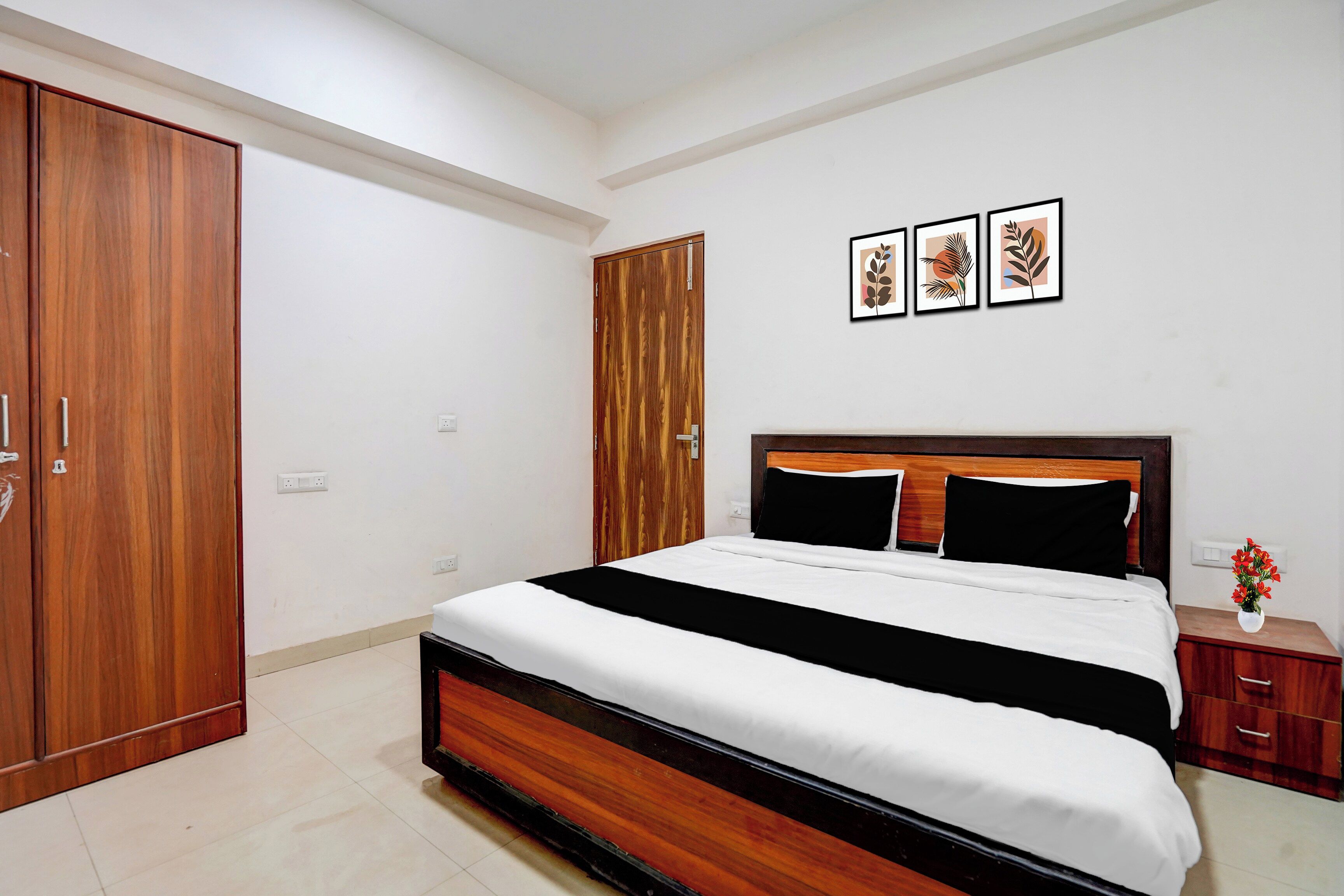 A bedroom with a wooden bed, a wardrobe, and a nightstand with a vase of flowers.