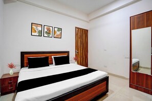 A hotel room with a bed, a wardrobe, a mirror, and three framed artworks on the wall. - Hotel O Sector 49 Noida (Noida)
