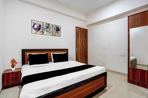 A bedroom with a bed, a nightstand, a mirror, and a wall-mounted artwork. - Hotel O Sector 49 Noida (Noida)