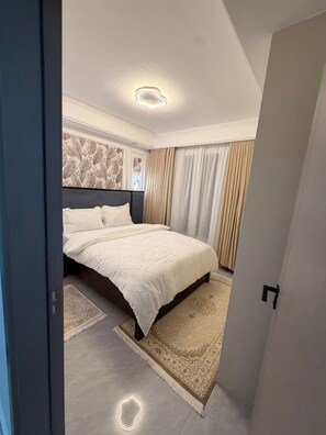 A modern bedroom with a large bed, a patterned headboard, a decorative wall, and a light-colored floor. - Bellace Haven | Stylish Holiday Homes & Short-Stay Accommodation in Kenya (Nairobi)