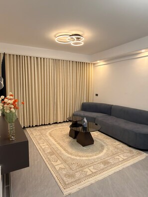 A modern living room with a sofa, a glass coffee table, a decorative vase with flowers, and a patterned rug. - Bellace Haven | Stylish Holiday Homes & Short-Stay Accommodation in Kenya (Nairobi)