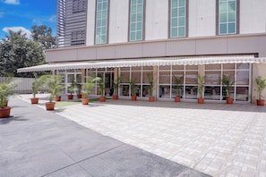 A building with a covered outdoor area, potted plants, and a tiled walkway.