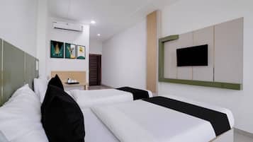 Habitación de hotel con dos camas, un televisor de pantalla plana montado en la pared y una mesita con tetera y tazas.