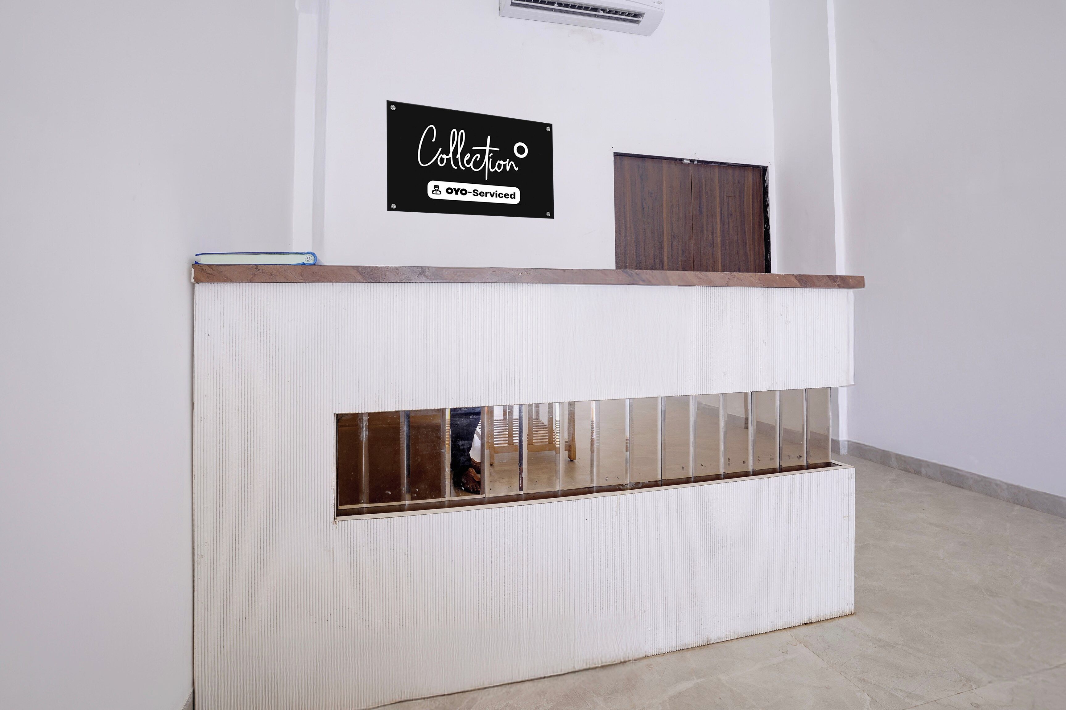 A reception desk with a sign above it, a wooden panel, and a mirrored section.