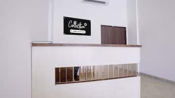 Una mesa de recepción con un letrero encima, un panel de madera y una sección espejada.