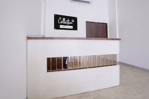 A reception desk with a sign above it, a wooden panel, and a mirrored section.