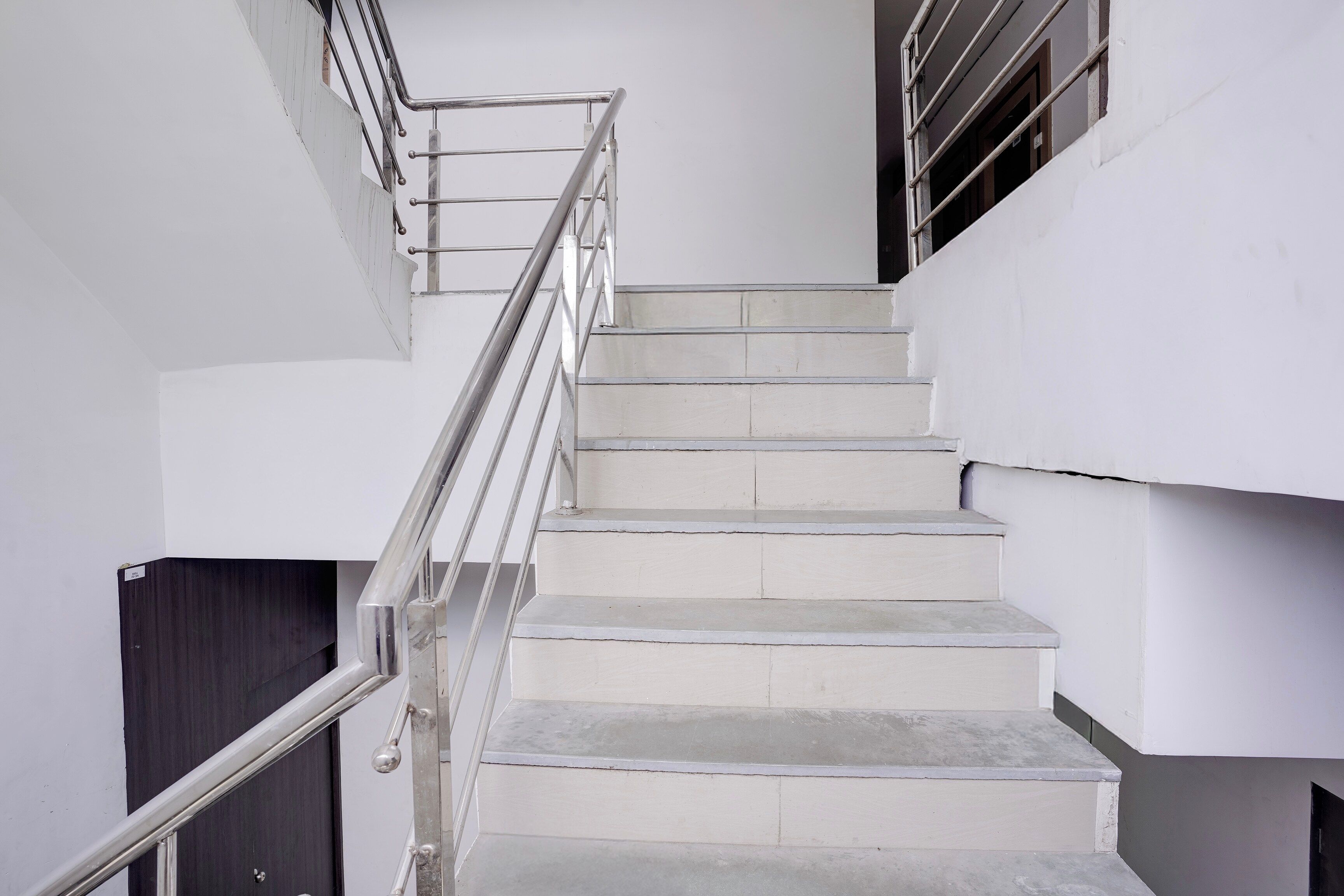 Una escalera con barandillas de metal y paredes blancas.