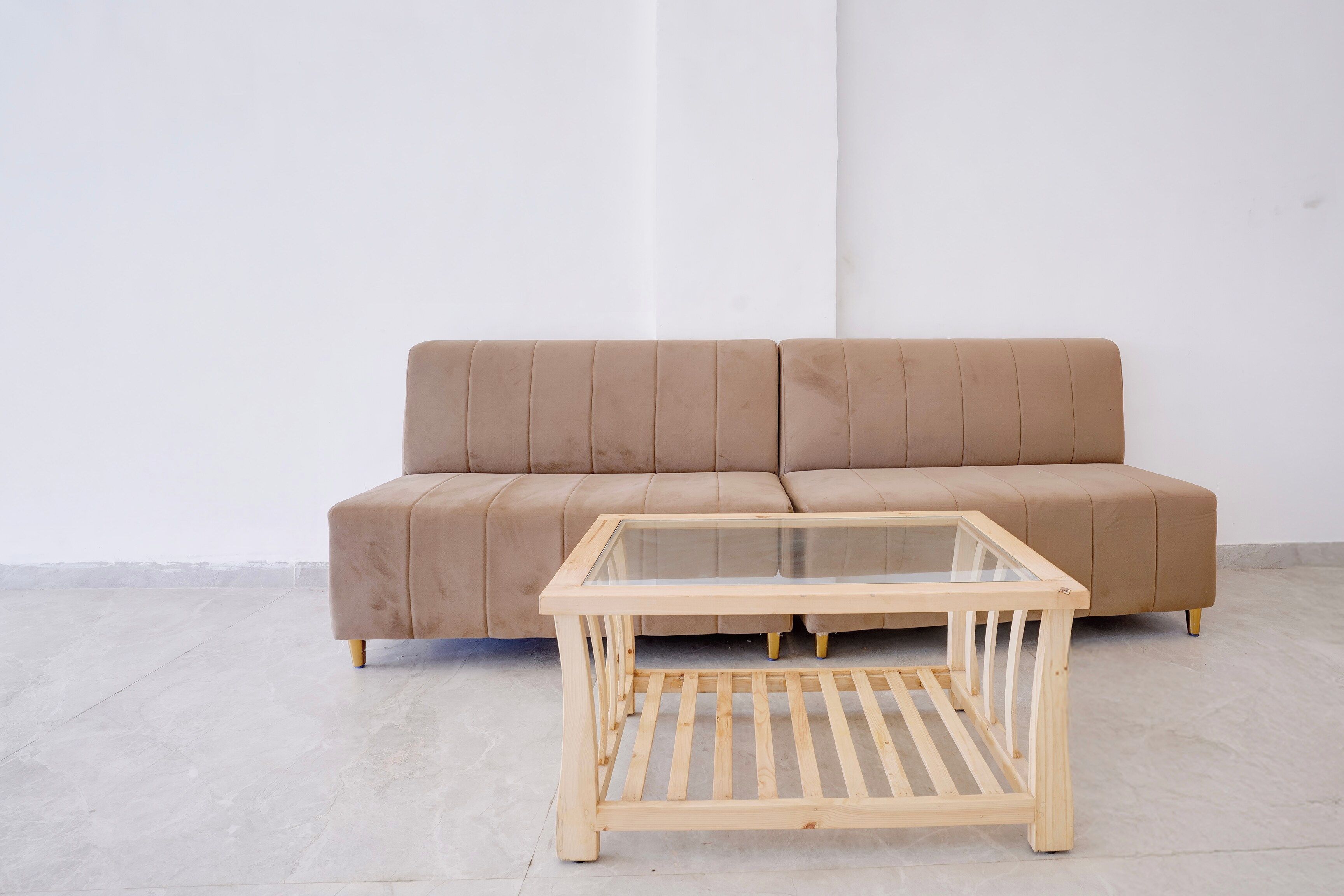 Un divano beige con un tavolino da caffè in vetro davanti.