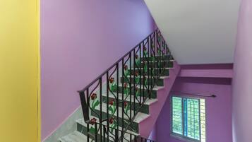 Una escalera con una pared morada y un ventanal con vistas al verdor.