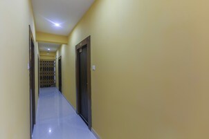 Un pasillo largo y estrecho con puertas a ambos lados, que conduce a una habitación con ventana de barrotes.