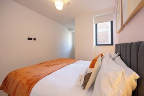 A modern bedroom with a bed, a window, and a wall-mounted light fixture. - Modern 1 BR Flat in Liverpool City Centre (Liverpool)