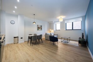 A modern living room with a dining area, a sofa, a TV, and a window with a view. - Modern 1 BR Flat in Liverpool City Centre (Liverpool)