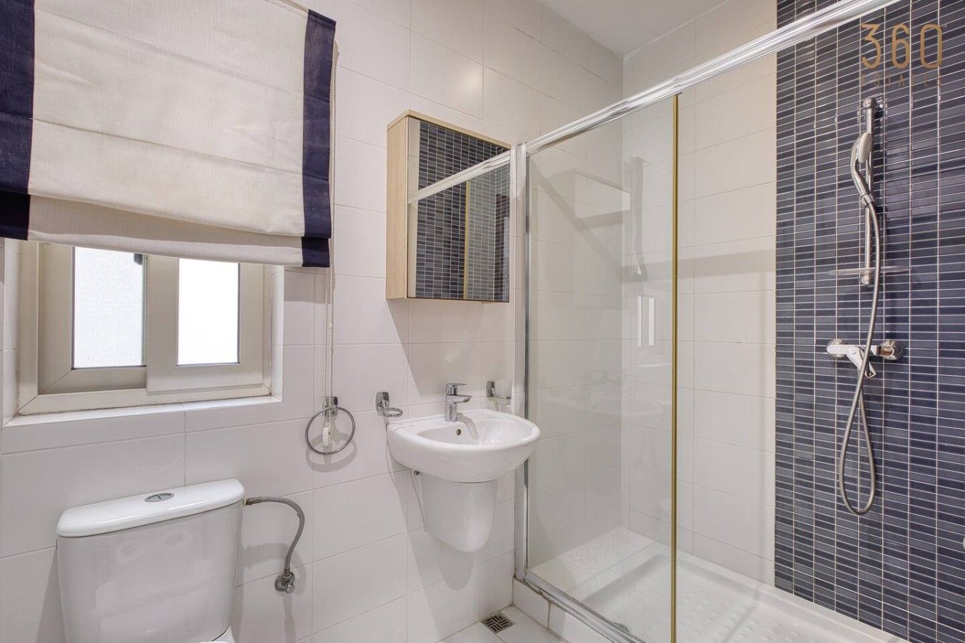 A bathroom with a toilet, sink, and glass-enclosed shower area.