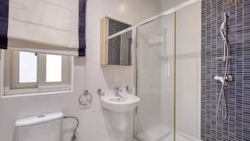 A bathroom with a toilet, sink, and glass-enclosed shower area.