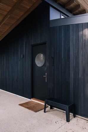 A black door with a circular window, a bench, and a wooden ceiling. - Ukiyo House - 2 Bedroom “The Floating World” (Port Willunga)