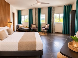 Habitación de hotel moderna con una cama grande, dos zonas de estar y vistas a zonas verdes.