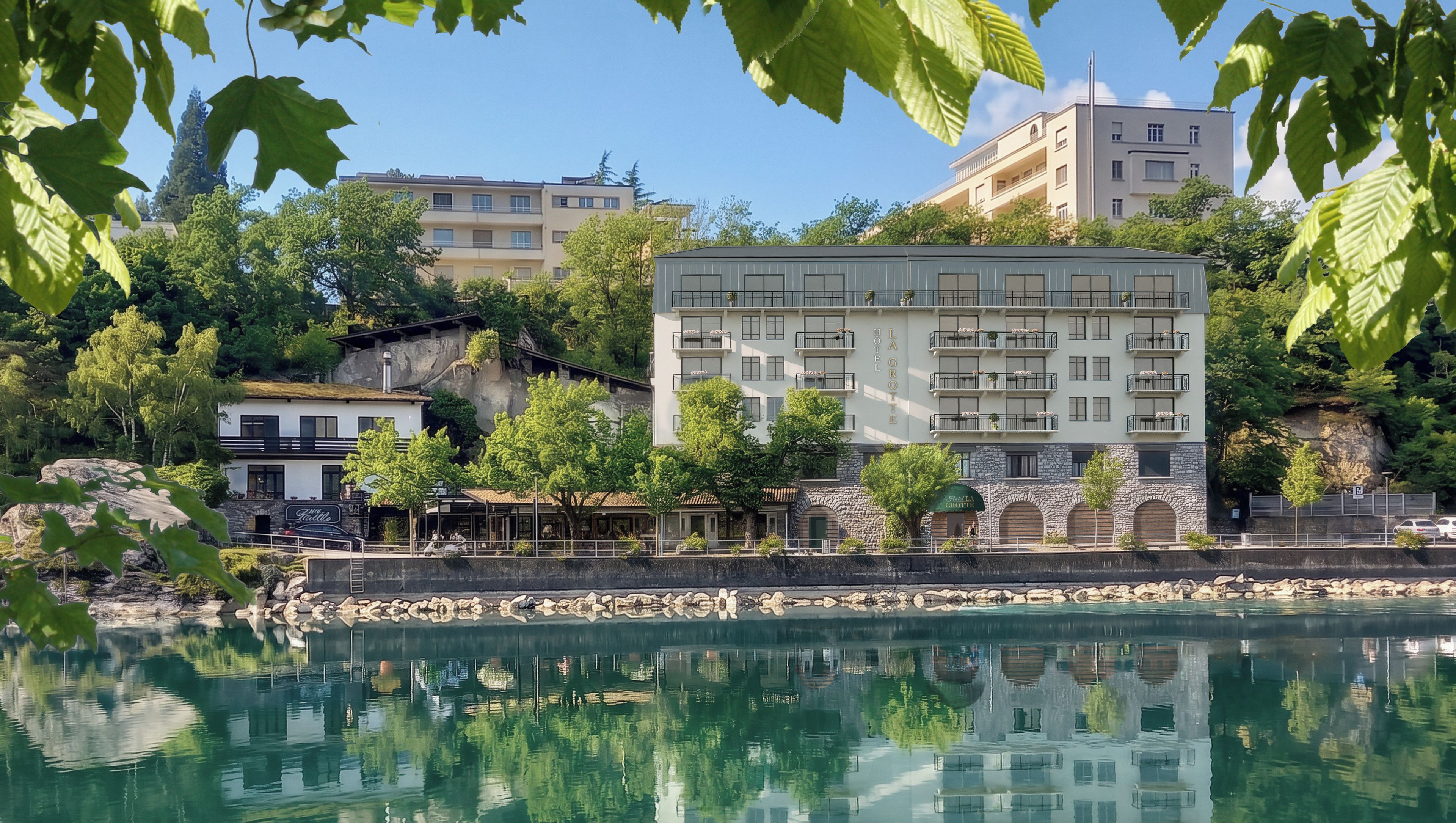 Un bâtiment doté de nombreux balcons et d’une façade en pierre, situé au bord d’une étendue d’eau calme où se reflètent les environs.