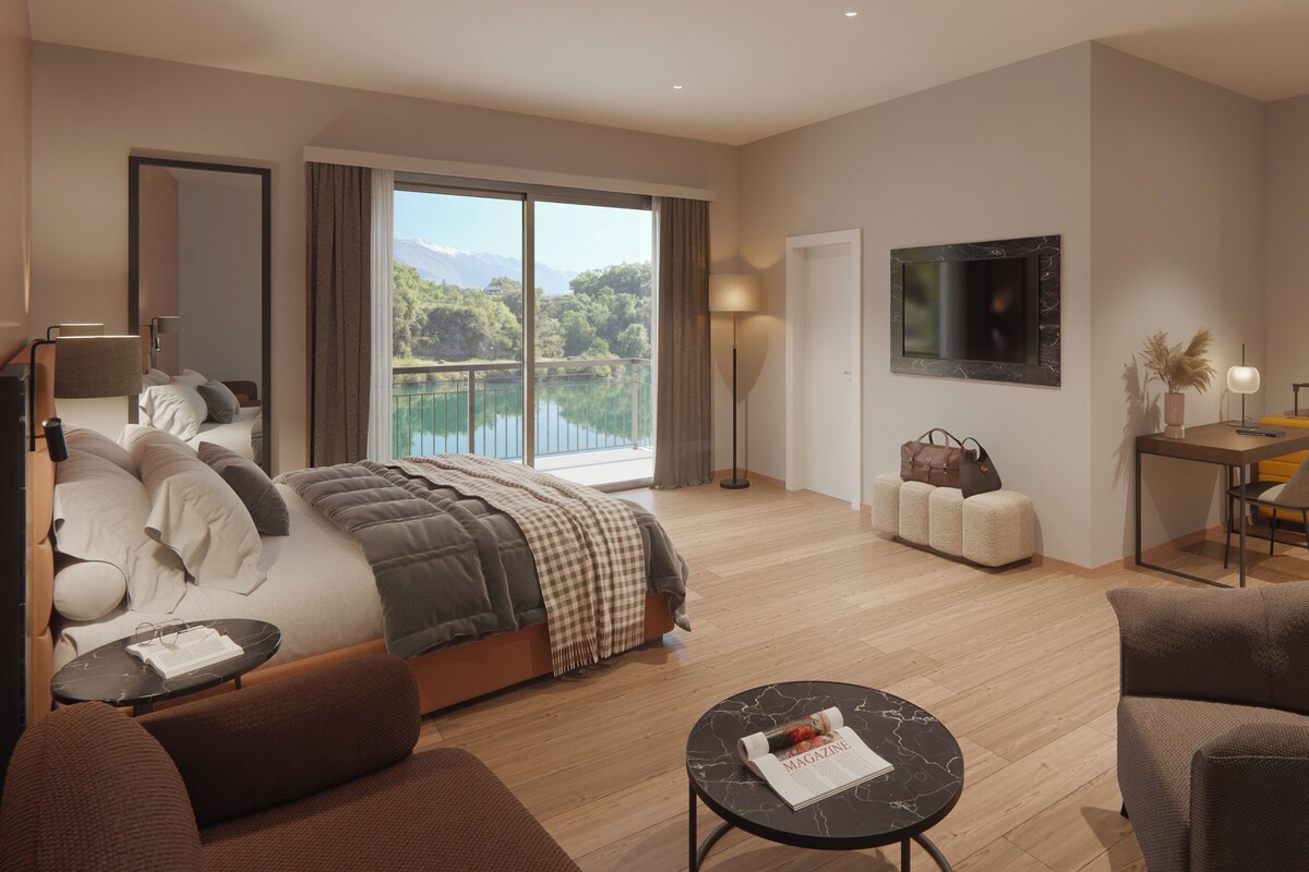 Habitación de hotel moderna con una cama grande, un escritorio, una silla y vistas a un lago.