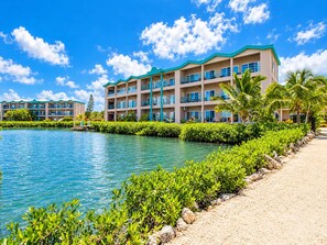 A multi-story hotel with a pool, surrounded by lush greenery and palm trees. - Renovated Lagoon View Condo with Pool in San Pedro (San Pedro)
