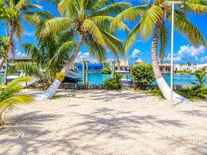 A resort with a sandy beach, palm trees, a pool, and a blue building. - Renovated Lagoon View Condo with Pool in San Pedro (San Pedro)