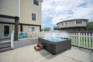 A hot tub on a patio with a white fence, a wooden deck, and a house in the background. - 9BR Ocean Estate • Pool • Hot Tub, 350 FT to Beach (Virginia Beach)