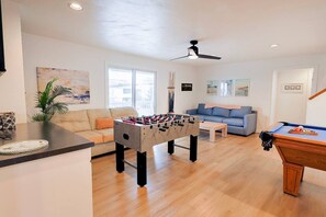 A living room with a foosball table, a pool table, a sofa, and a ceiling fan. - 9BR Ocean Estate • Pool • Hot Tub, 350 FT to Beach (Virginia Beach)