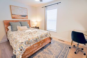 A bedroom with a bed, bedside tables, a chair, a window with blinds, and a painting on the wall. - 9BR Ocean Estate • Pool • Hot Tub, 350 FT to Beach (Virginia Beach)