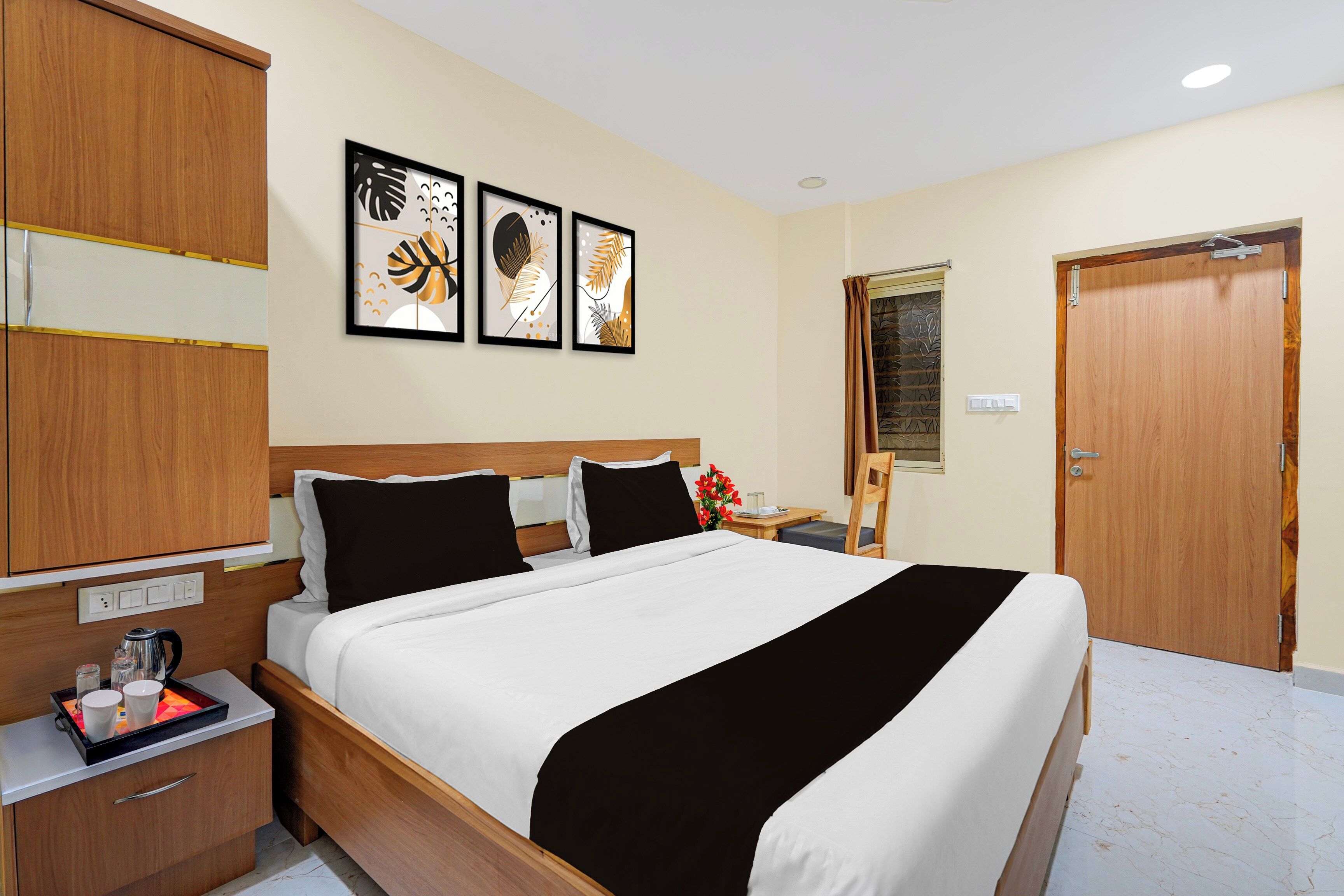 Ein Hotelzimmer mit Bett, Nachttisch und Kleiderschrank. An der Wand hängen drei gerahmte Kunstwerke.