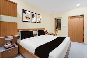 Ein Hotelzimmer mit Bett, Nachttisch und Kleiderschrank. An der Wand hängen drei gerahmte Kunstwerke.
