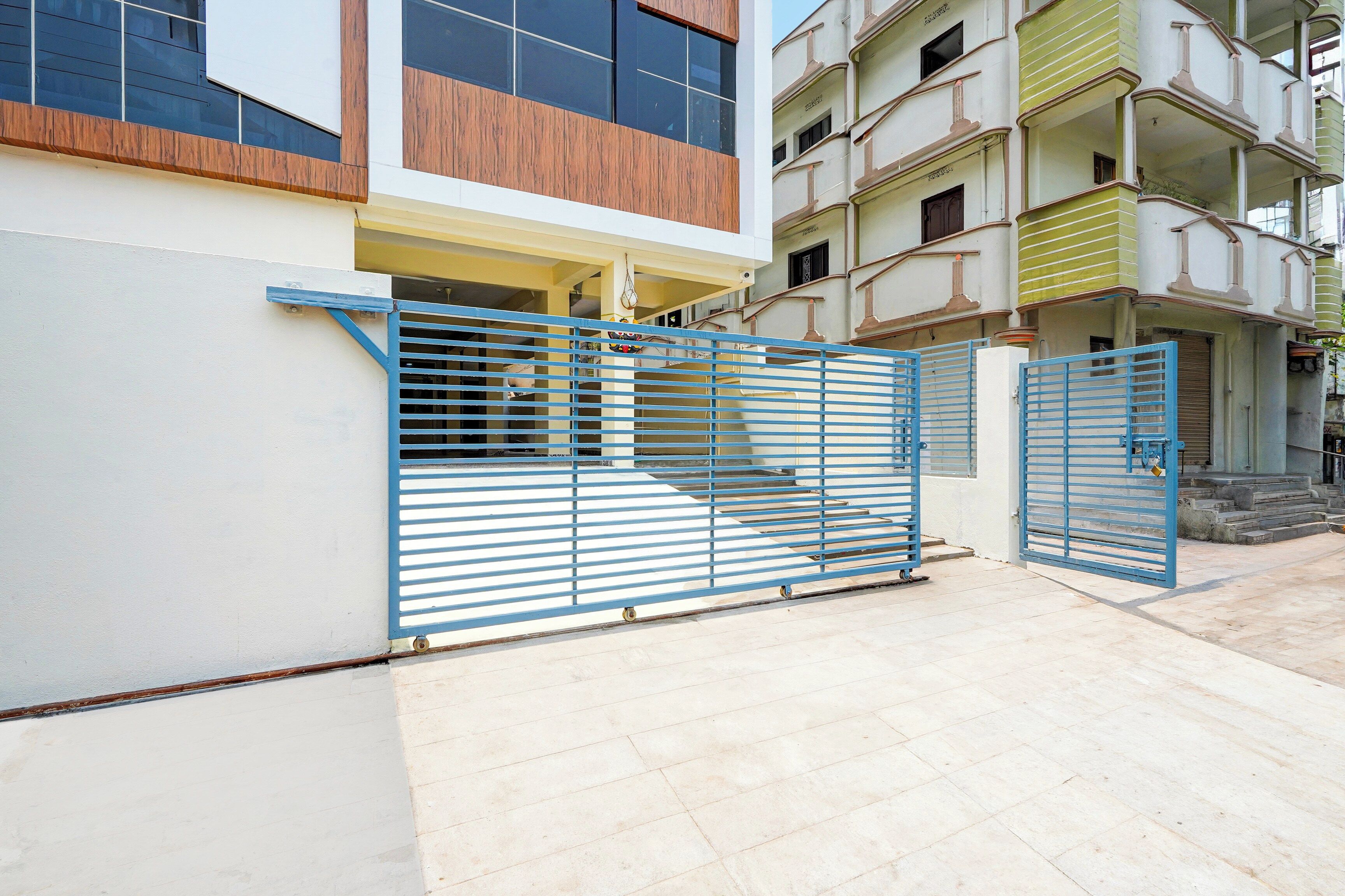 Ein befestigter Eingang zu einem Gebäude mit modernem Design, mit einem blauen Metallgitter und einem Betonboden.