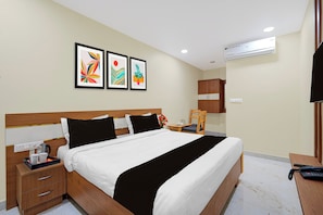 Ein Hotelzimmer mit Bett, Nachttisch, Wandairconditioner und Ablagefläche.