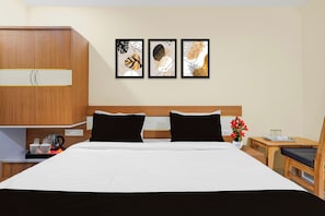 Ein Hotelzimmer mit einem Bett, Nachttischen, einem Holzschrank und drei gerahmten Wandbildern.