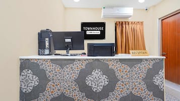 Ein Empfangsbereich mit einer Rezeption, einem Computer, einem Bildschirm und einem entsprechenden Schild.