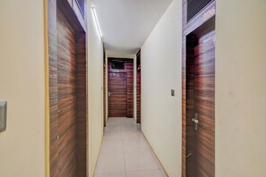 Un pasillo con puertas de madera, piso de baldosas y una lámpara en el techo.
