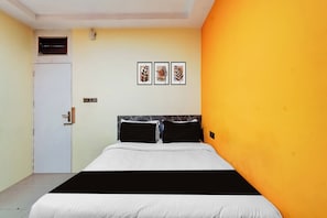 Una habitación de hotel con una cama, una puerta y una pared decorada con tres cuadros.