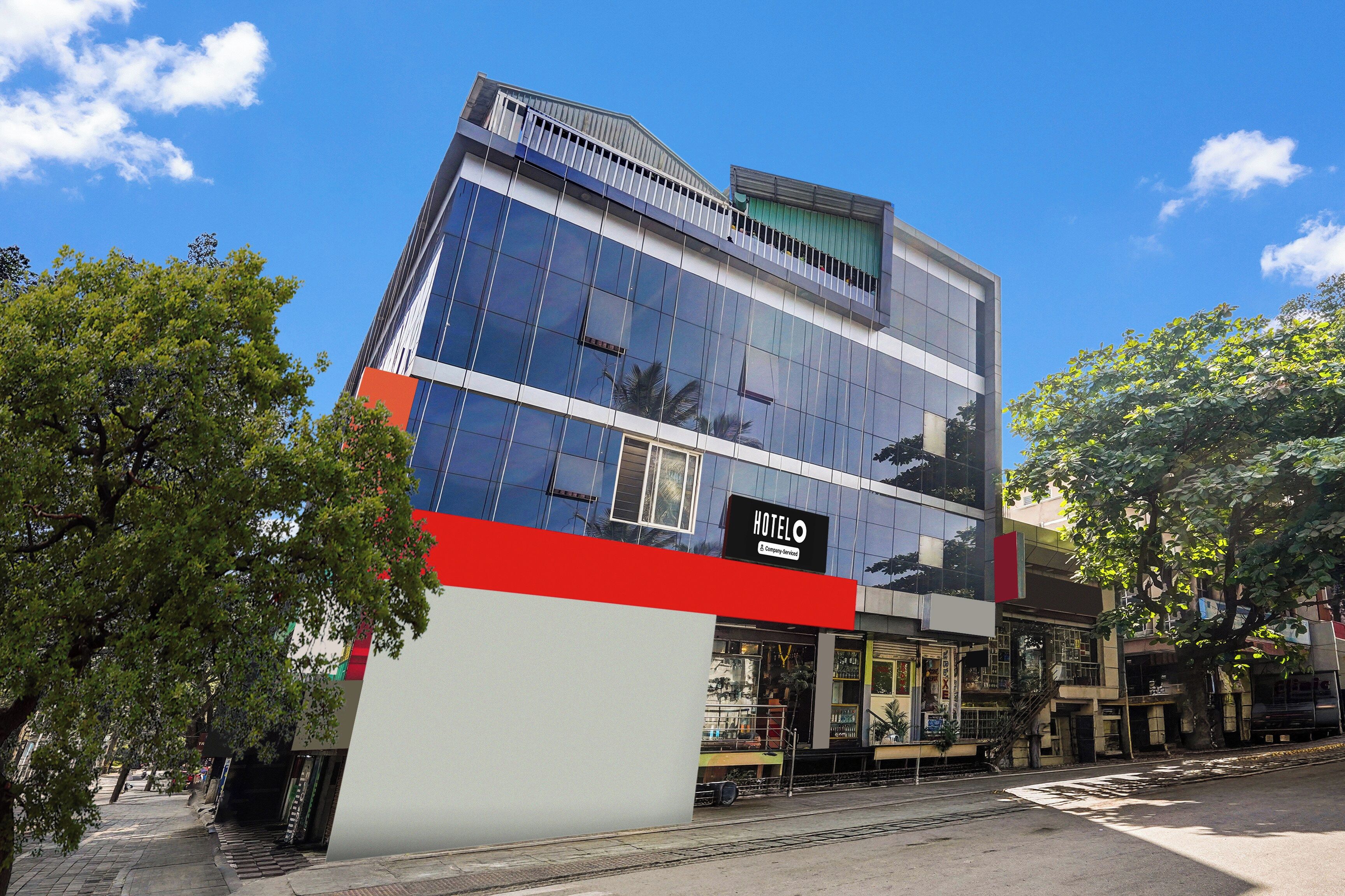 A modern hotel building with a prominent 'HOTELO' sign, large windows, and a red and white facade.