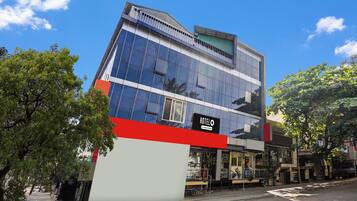 A modern hotel building with a prominent 'HOTELO' sign, large windows, and a red and white facade.