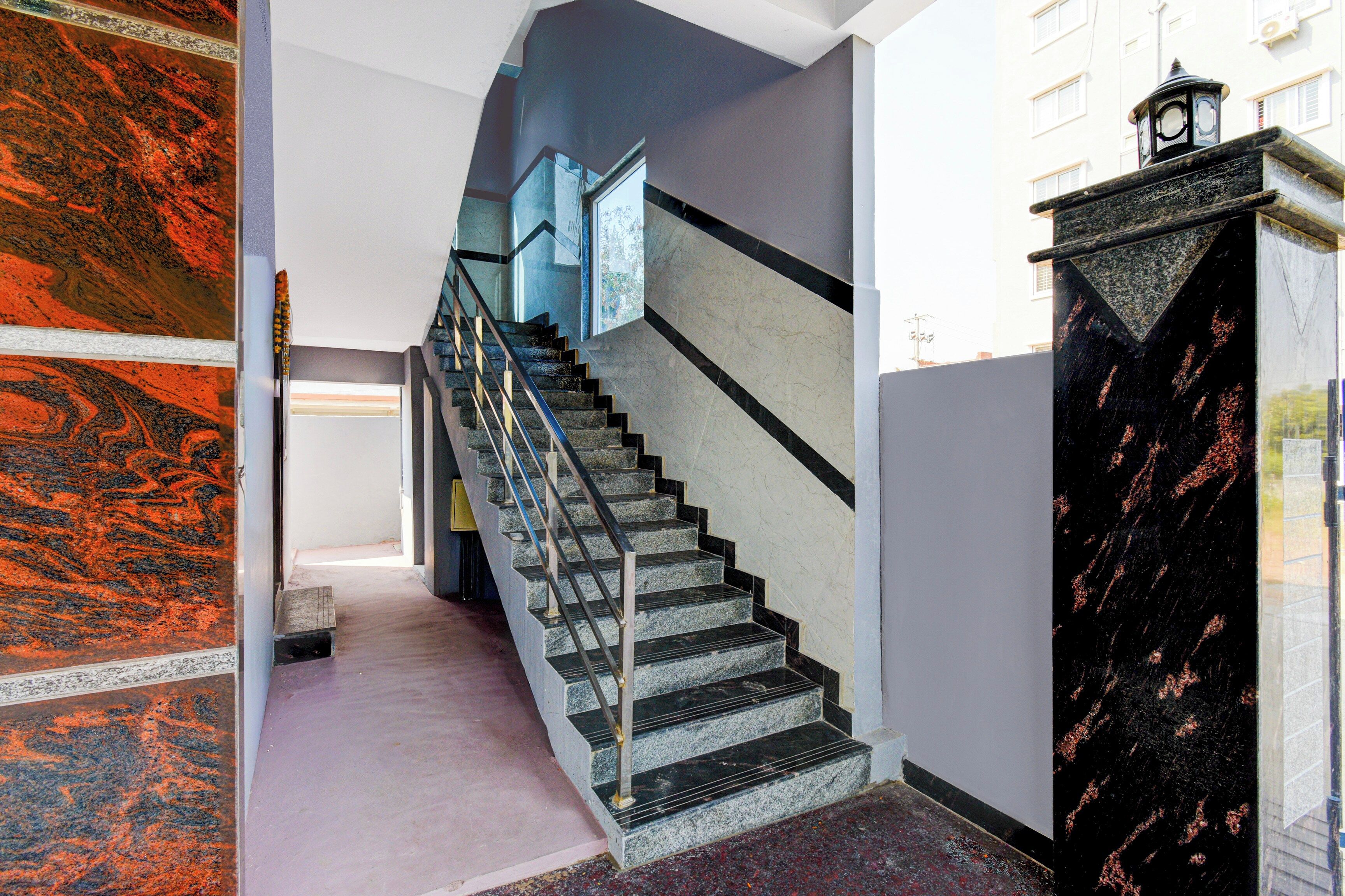 A staircase with a metal handrail and a black wall with a decorative pattern.