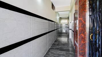 Un largo y estrecho pasillo con paredes de baldosas blancas y negras, y piso de mármol negro.