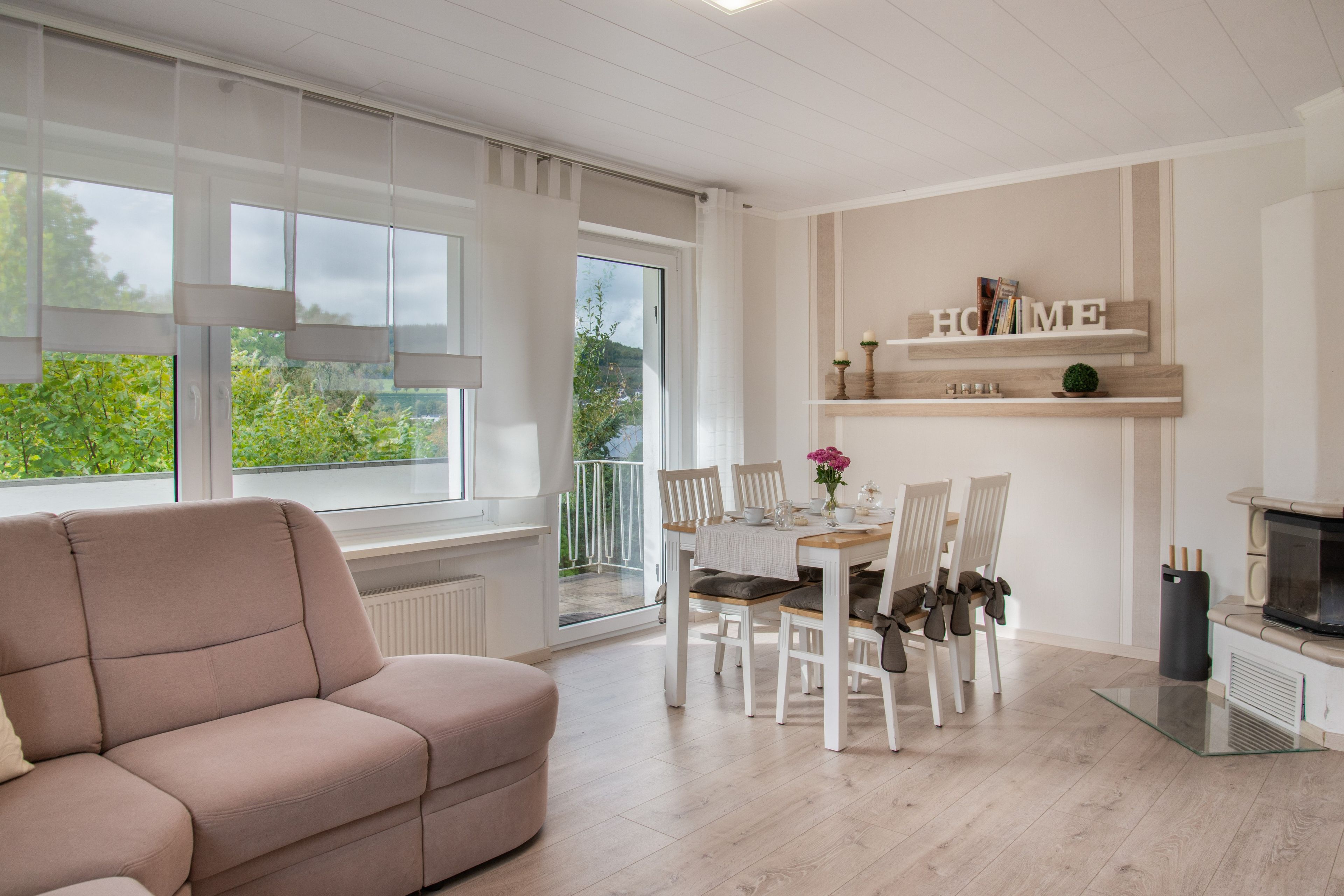 Ein modernes Wohnzimmer mit einer Couch, einem Esstisch, Stühlen und einer Küchenzeile inklusive Mikrowelle.