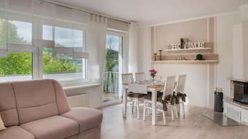 Ein modernes Wohnzimmer mit einer Couch, einem Esstisch, Stühlen und einer Küchenzeile inklusive Mikrowelle.