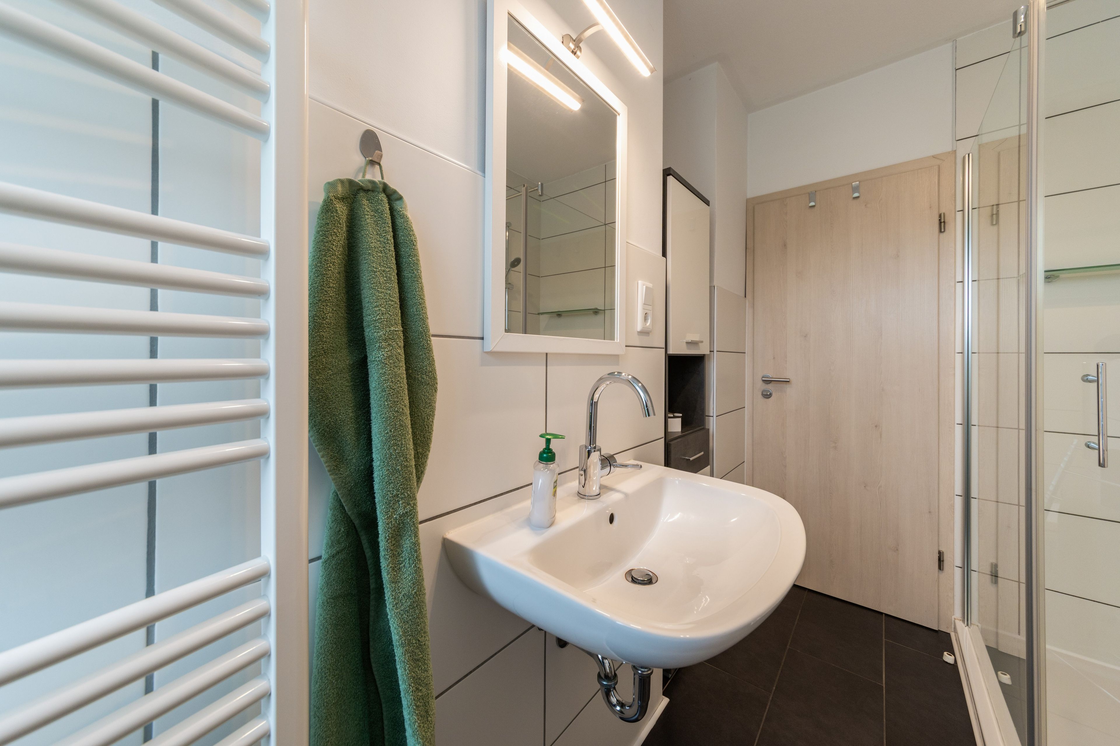 A bathroom with a white sink, a mirror, and a towel hanging on a rack.