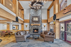 Eine geräumige Lobby mit Kamin aus Stein, Ledersofas und einer Kristallleuchter.