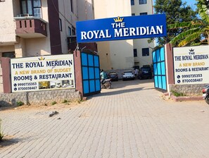 L’entrée d’un hôtel, avec une enseigne indiquant « The Royal Meridian » et une banderole faisant la publicité de chambres à prix abordables et d’un restaurant.