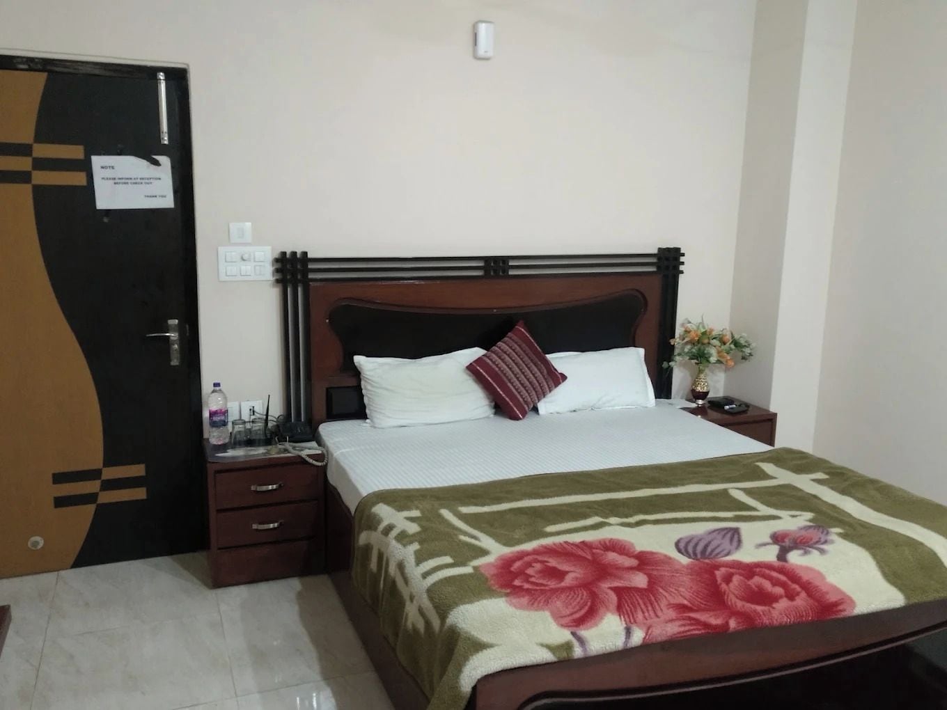 A bedroom with a bed, nightstand, and a door with a note.